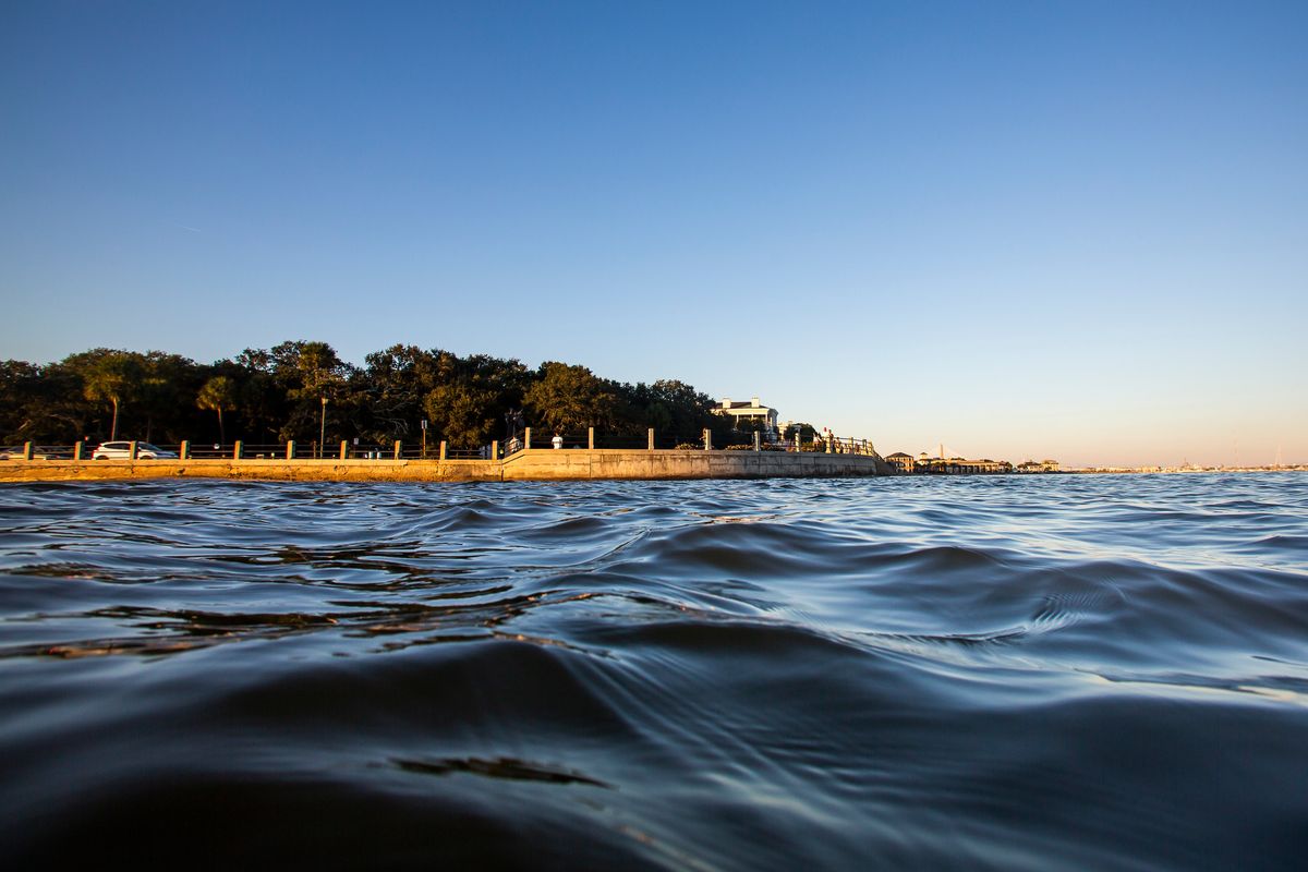 As high tide laps against the sea wall on Nov. 13, 2020, tourists walk down the Battery in Charleston, S.C. (Mic Smith)
