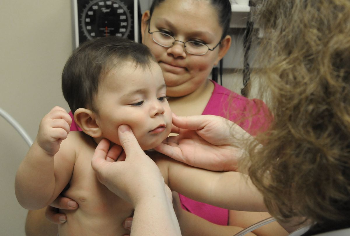 Gabriela Gadayan holds her son, Cameron, 7 months, during an exam by Dr. Lanie Cox on Thursday at the Spokane Falls Family Clinic.  Cameron is covered under a state-funded health insurance program.  (Photos by DAN PELLE / The Spokesman-Review)