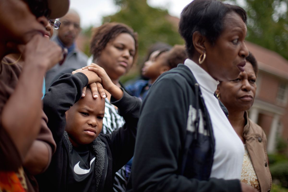 Chaz Johnson, 10, left, joins his mother Yhonna Flowers, rear, and grandmother, retired Atlanta police Det. Jaqueline Barber, near right, during a news interview along with members of Occupy Atlanta and fellow officers outside Barber's home Monday, Oct. 8, 2012, in Fayetteville, Ga. Less than a year after Occupy Atlanta members clashed with police in riot gear in a downtown park, they're now protesting alongside officers to help Barber avoid losing her home to foreclosure. Barber said she is under threat of eviction after her medical bills mounted, partly because of a diagnosis of multiple myeloma, a form of blood cell cancer. If she's evicted along with her daughter and four granchildren, she expects that she will be homeless. (David Goldman / Associated Press)