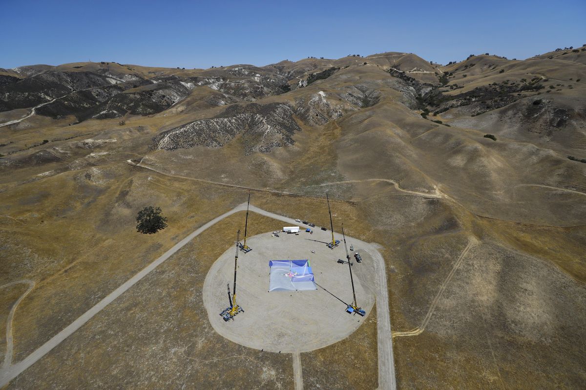 In this Monday, July 25, 2016 photo, cranes stand on the ground as production crew members set up a net about one-third the size of a football field and 20 stories high ahead of skydiver Luke Aikins’ landing attempt without a parachute or wing suit in Simi Valley, Calif. (Jae C. Hong / Associated Press)
