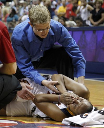 Fever guard Briann January is tended to by trainer Craig Stull after the Lewis and Clark grad was injured against Phoenix. (Associated Press)