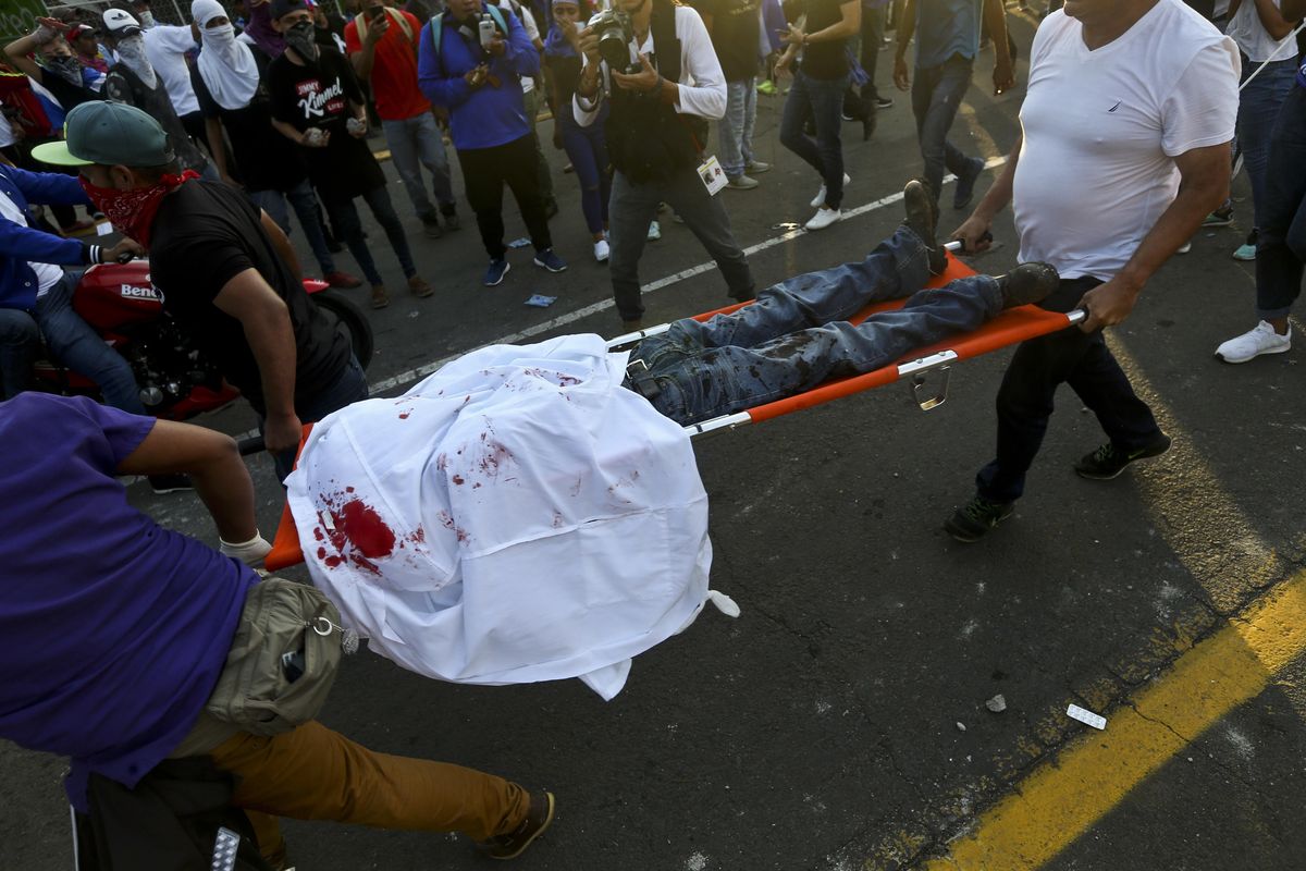 In this May 30, 2018 file photo, a dead demonstrator who was shot in the head is carried by paramedics after clashes erupted during a march against Nicaragua’s President Daniel Ortega in Managua, Nicaragua. More than 300 people have been killed in violence since mid-April. (Esteban Felix / Associated Press)