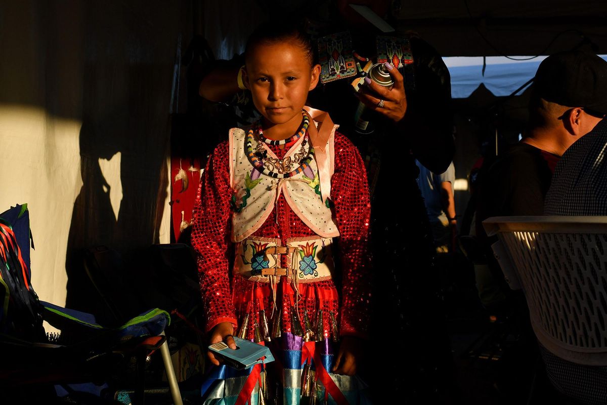 Scarlett Scalplock, of Mesa Arizona, waits patiently as her mother Tia Scalplock does her hair, before she danced during the Julyamsh Powwow on Friday, July 26, 2019, at Kootenai County Fairgrounds in Coeur d