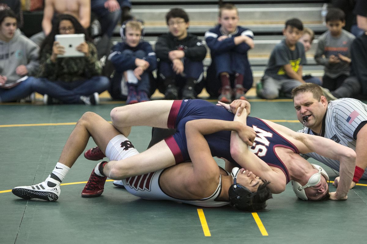 Clai Quintanilla of North Central ties up Mt. Spokane’s Jesse Miesler  in their 132 pound match, Feb. 4, 2017, at Shadle Park High School. Wrestling referee Chris Cluever officiates at right. Because of a shortage of officials, new referees are fast-tracked into officiating varsity matches within two or three years. (Dan Pelle / The Spokesman-Review)