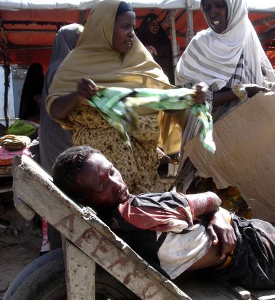 An injured Somali lies in a wheelbarrow, after mortar shells  landed in  a market in Mogadishu  on Tuesday.  (Associated Press / The Spokesman-Review)