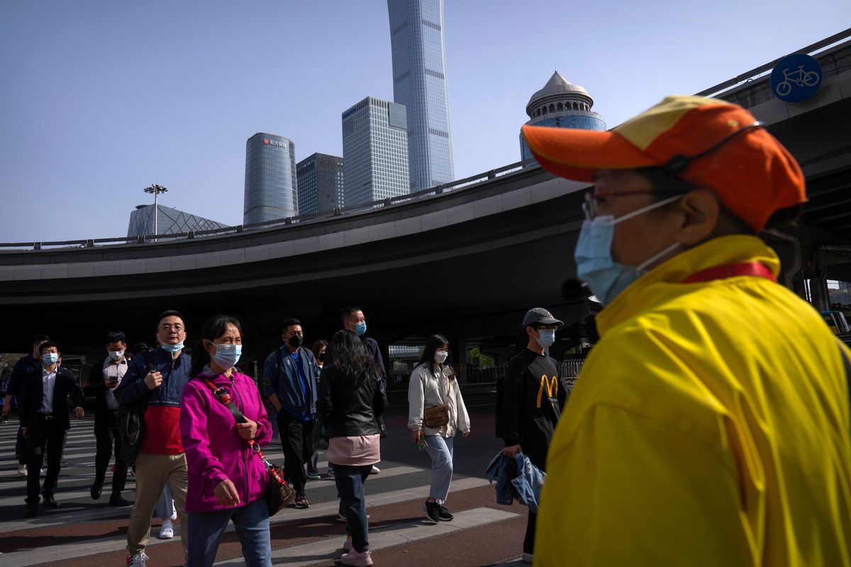 Commuters wearing face masks Tuesday walk across an intersection in the central business district in Beijing.  (Mark Schiefelbein)