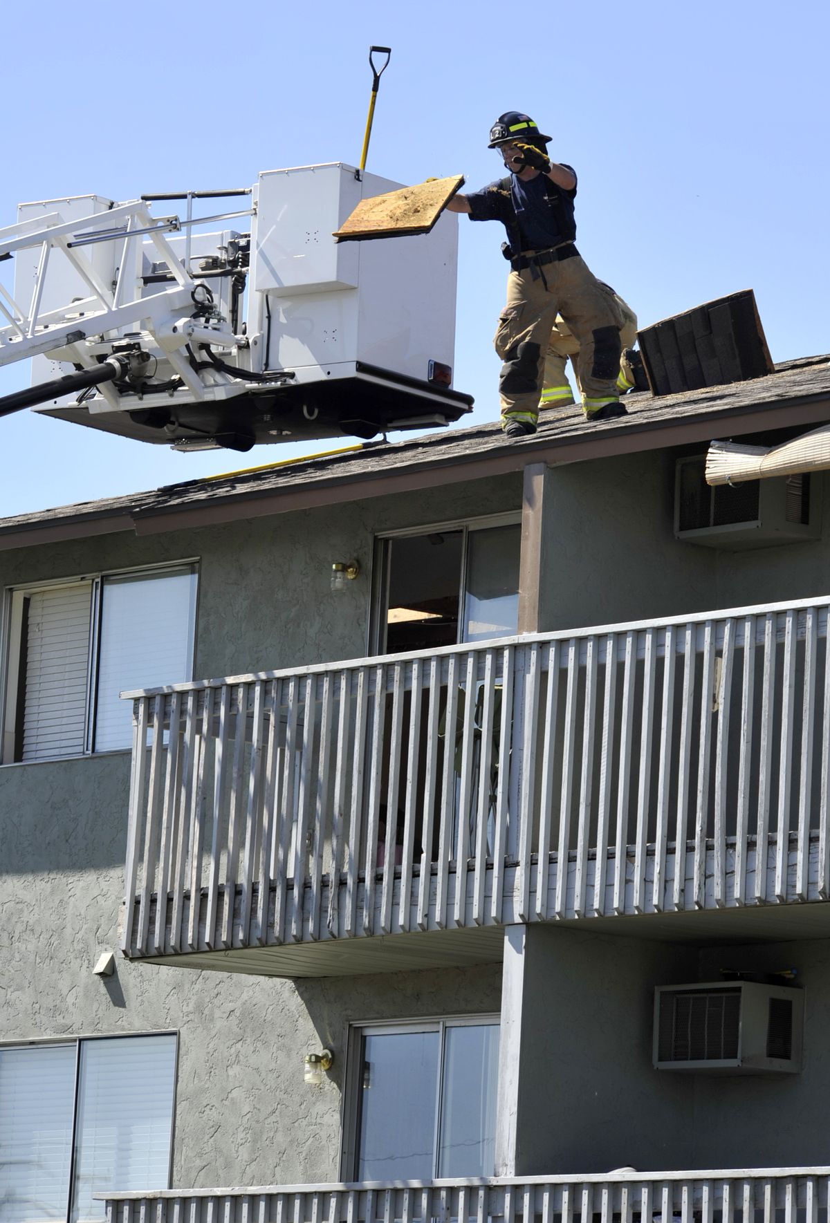 A Spokane firefighter tosses debris from the roof of a three-story apartment building Aug. 24, 2011, after a ceiling fan started a fire and burned the roof at the corner of Boone Avenue and Nelson Street in Spokane. (Dan Pelle / The Spokesman-Review)