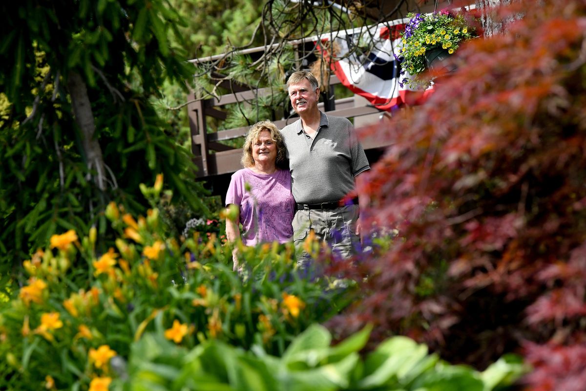 Larry Vail and Carol Holter pose for a photo in their garden on Tuesday, July 2, 2019, at their home in Nine Mile Falls, Wash. (Tyler Tjomsland / The Spokesman-Review)