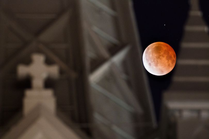 The moon glows a red hue during a lunar eclipse as it is framed between the steeples on the Annunciation Catholic Church in Houston, Tuesday, April 15, 2014. Tuesday's eclipse is the first of four total lunar eclipses that will take place between 2014 to 2015. (Johnny Hanson / Houston Chronicle)