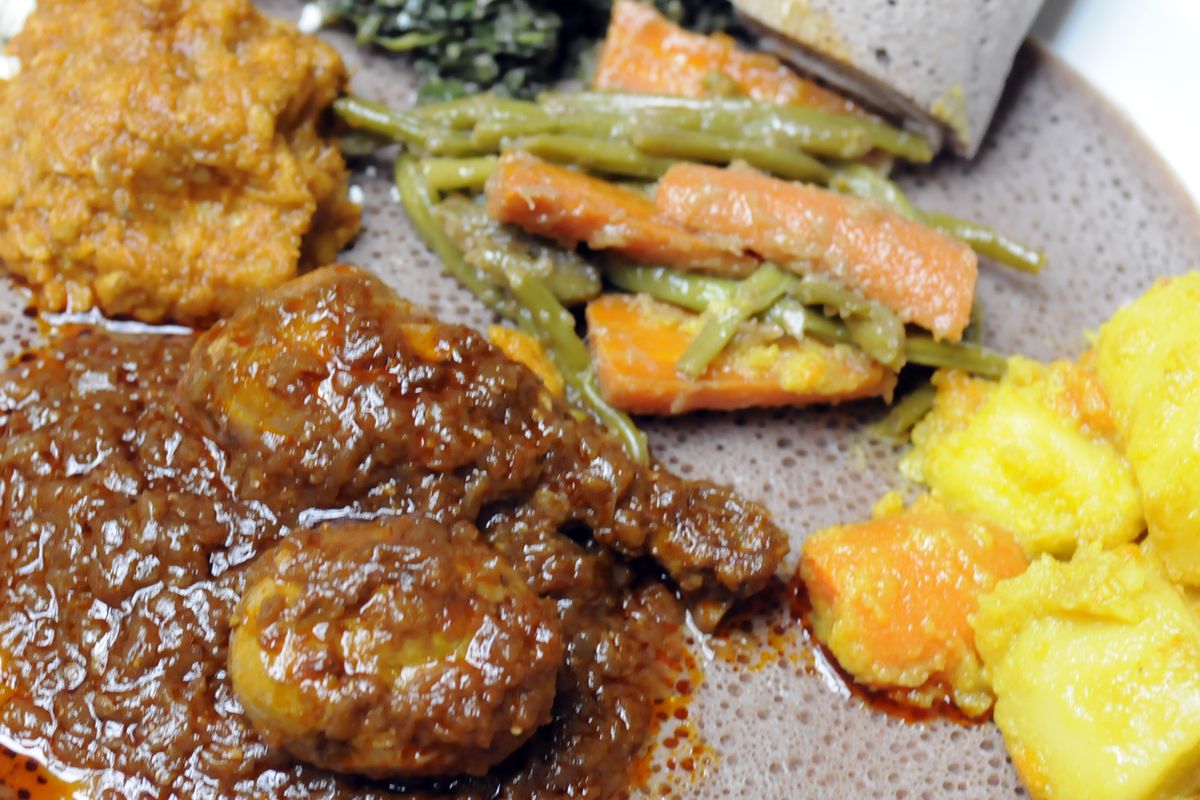 Stewed meats, vegetables and greens are arranged on a large platter at the Queen of Sheba restaurant.