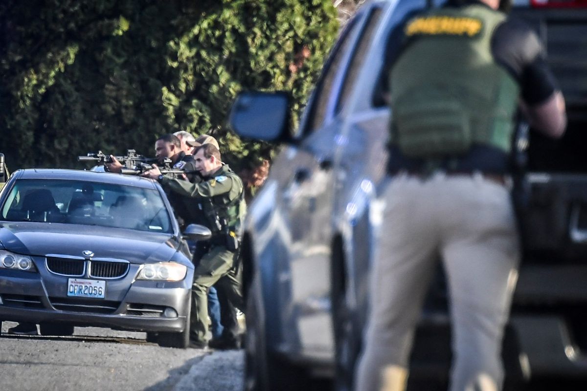 Law enforcement officers take cover with guns drawn as they engage a shooting suspect Thursday on South Glenrose Road.  (DAN PELLE/THE SPOKESMAN-REVIEW/THESPOKESMAN-REVIEW)