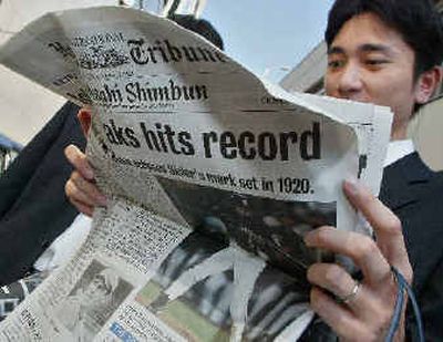 
A pedestrian reads the extra edition of a Tokyo newspaper flashing Ichiro Suzuki, who broke George Sisler's 84-year-old mark of 257 hits in a season. Ichiro had another hit Saturday, giving him 260.
 (AP / The Spokesman-Review)