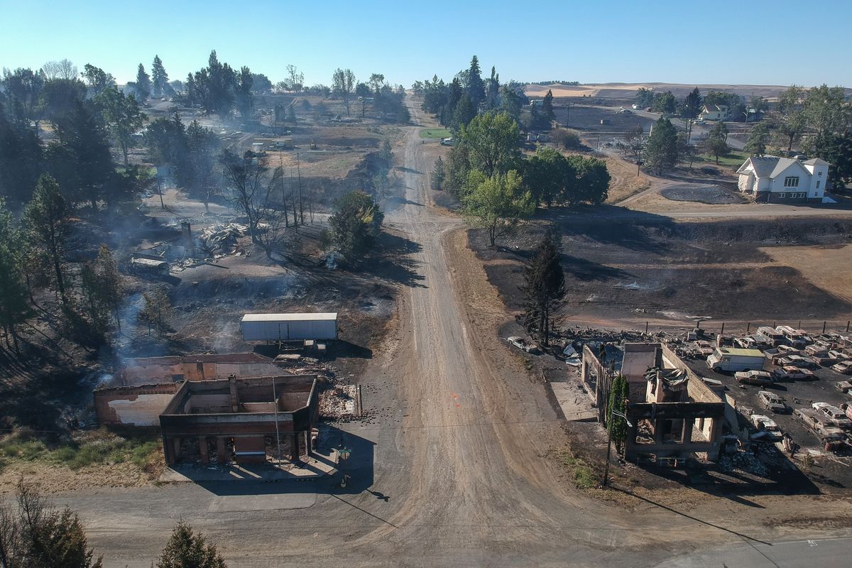 In downtown Malden, Washington, the former post office at lower left and another historic building at lower right still smolder Tuesday, one day after a fast-moving wildfire swept through the tiny town west of Rosalia.  (Jesse Tinsley/The Spokesman-Review)