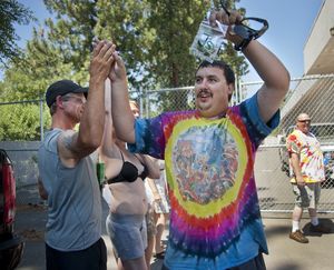 Mike Boyer races through the crowd showing off his 4 grams of pot he bought as the first in line to legally purchase marijuana at Spokane Green Leaf on Country Homes Boulevard.   Hundreds were lined up as sales in Washington began on Tuesday, July 8, 2014. (Dan Pelle / The Spokesman-Review)