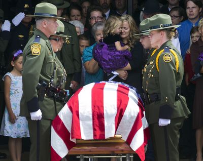 Christy Ivie, the wife of slain U.S. Border Patrol agent Nicholas Ivie, stands behind his casket after funeral services at The Church of Jesus Christ of Latter-day Saints meetinghouse in Sierra Vista, Ariz., on Monday. She is holding Raigan, 3. (Associated Press)