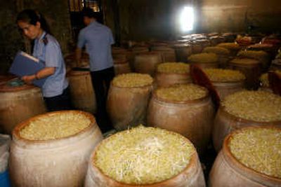 
Officials check some 90 barrels of bean sprouts at a workshop without a business license in Xiamen, in southeast China's Fujian province, Thursday. The workshop was found to have used bleaching powder to lighten the color of the bean sprouts. A government spokesman guaranteed the safety of Chinese exports on Thursday, in a rare direct commentary on rising international fears over Chinese products. Associated Press
 (Associated Press / The Spokesman-Review)