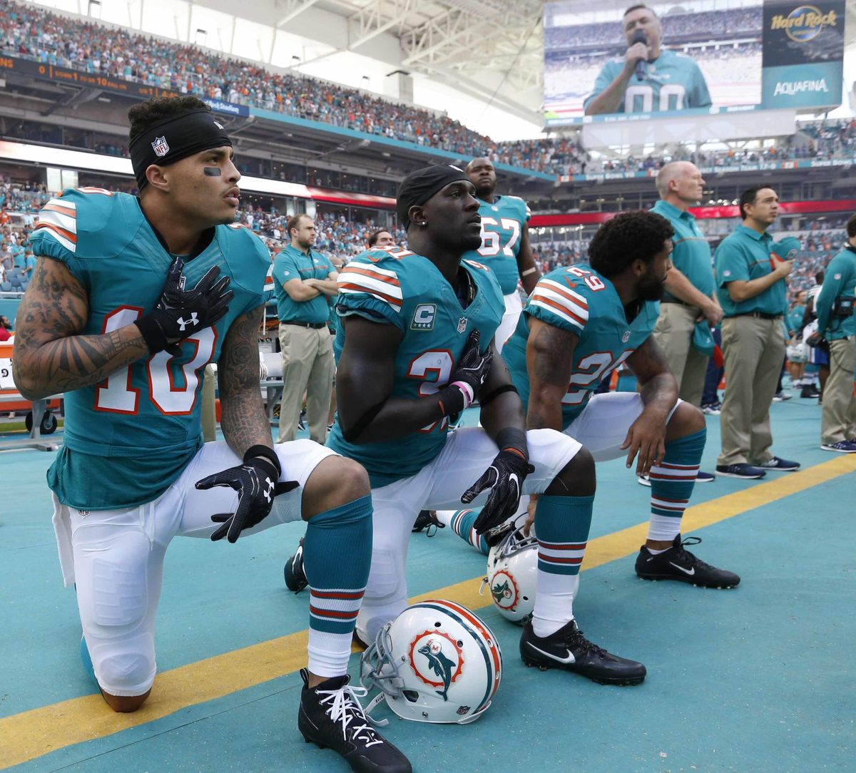 In this Sunday, Oct. 23, 2016, file photo, Miami Dolphins wide receiver Kenny Stills (10), free safety Michael Thomas (31) and defensive back Chris Culliver (29) kneel during the National Anthem before the first half of an NFL football game against the Buffalo Bills in Miami Gardens, Fla. Miami Dolphins players who protest on the field during the national anthem this season could be suspended for up to four games under a new team policy issued to players this week. The policy obtained by The Associated Press on Thursday, July 19, 2018 classifies anthem protests as conduct detrimental to the club, punishable by suspension without pay, a fine or both. (Wilfredo Lee / Associated Press)