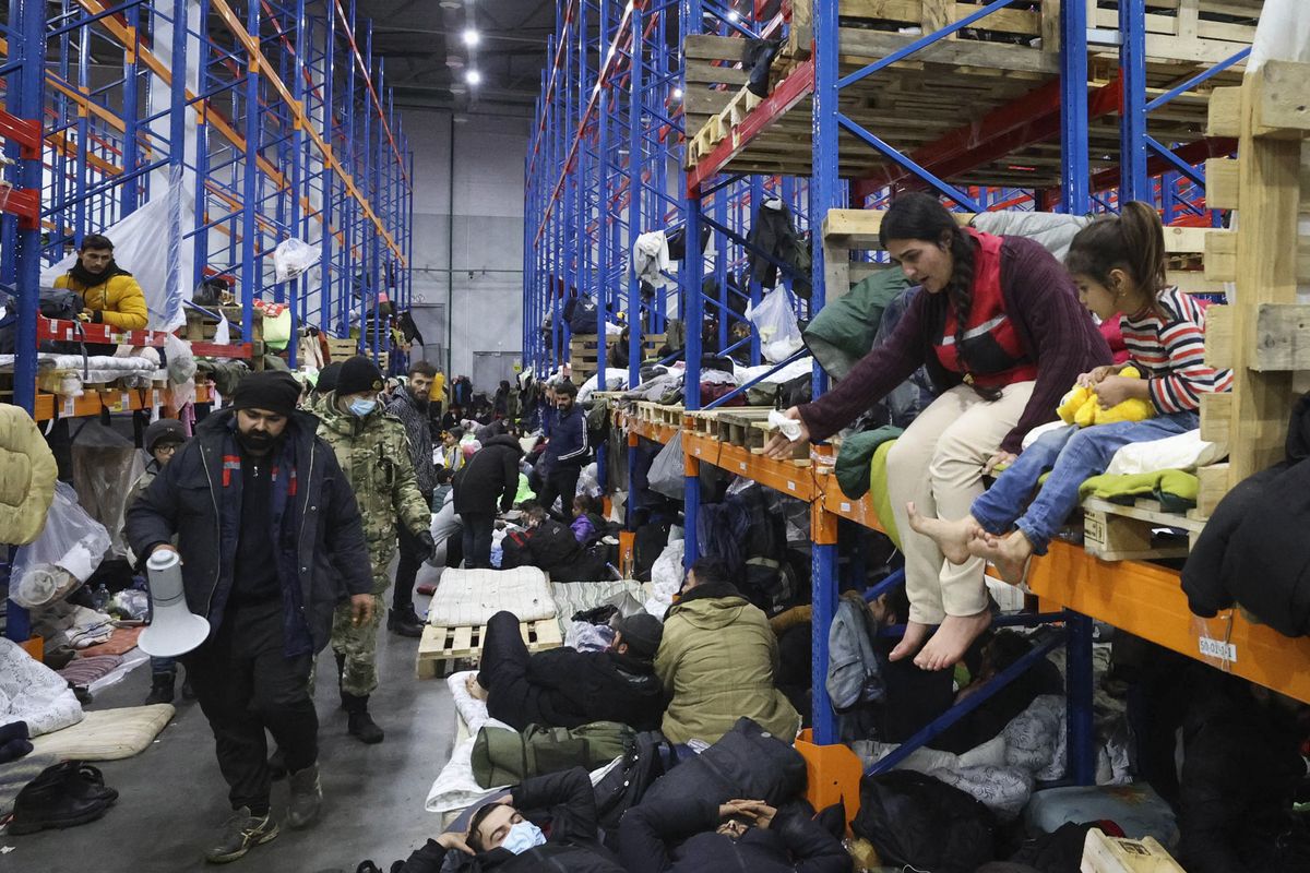 Migrants settle in a logistics center at the checkpoint "Kuznitsa" at the Belarus-Poland border near Grodno, Belarus, on Friday, Nov. 19, 2021. Polish authorities said Friday there are no more migrants camping along the Belarus side of the European Union