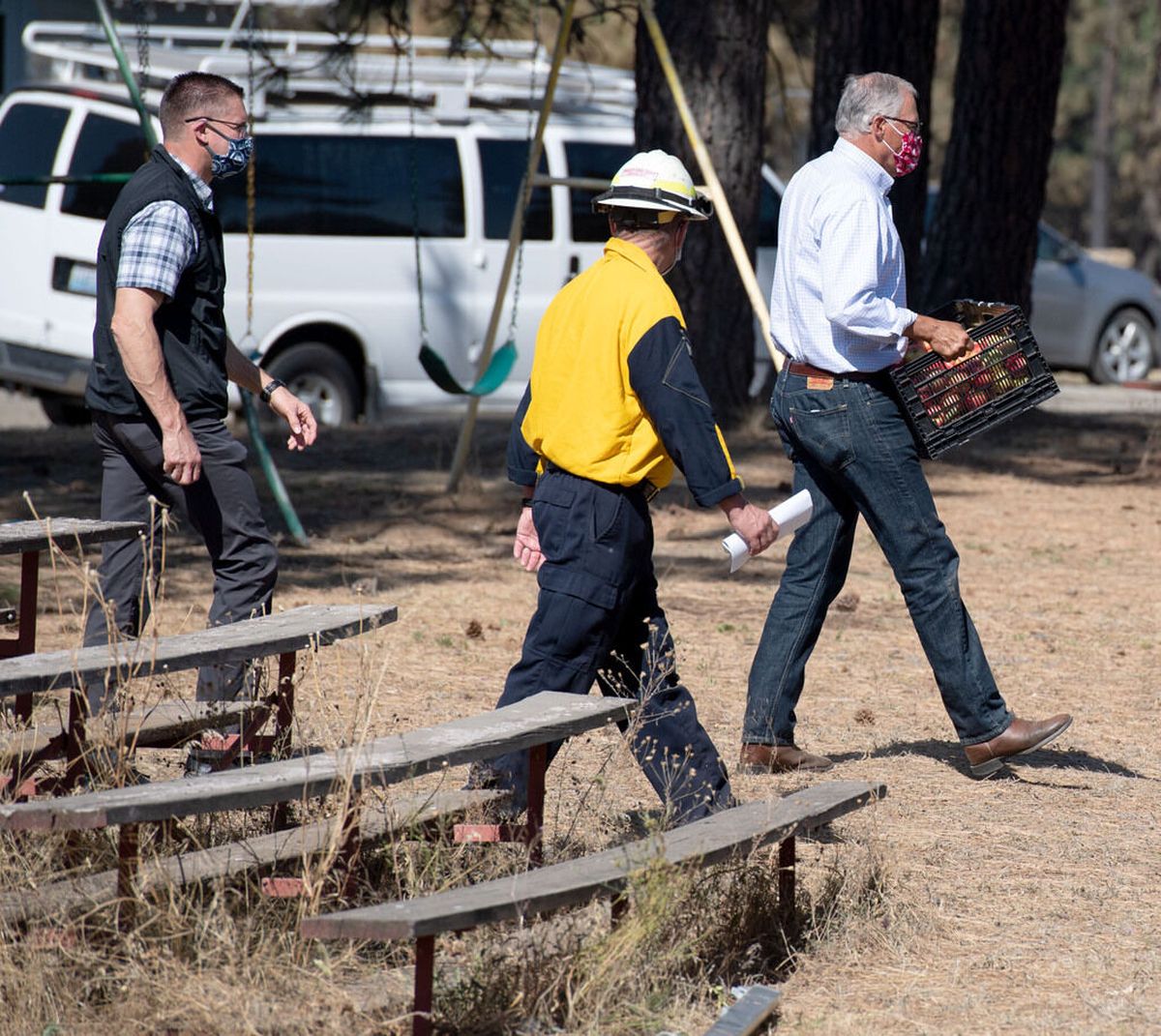 On a visit to fire-devastated Malden, Washington, last month Gov. Jay Inslee, right, arrives at a town meeting with a basket of fresh honeycrisp apples picked from the trees at the governor’s mansion. The fruit was infested with apple maggot larvae.  (Colin Mulvany / The Spokesman-Review)