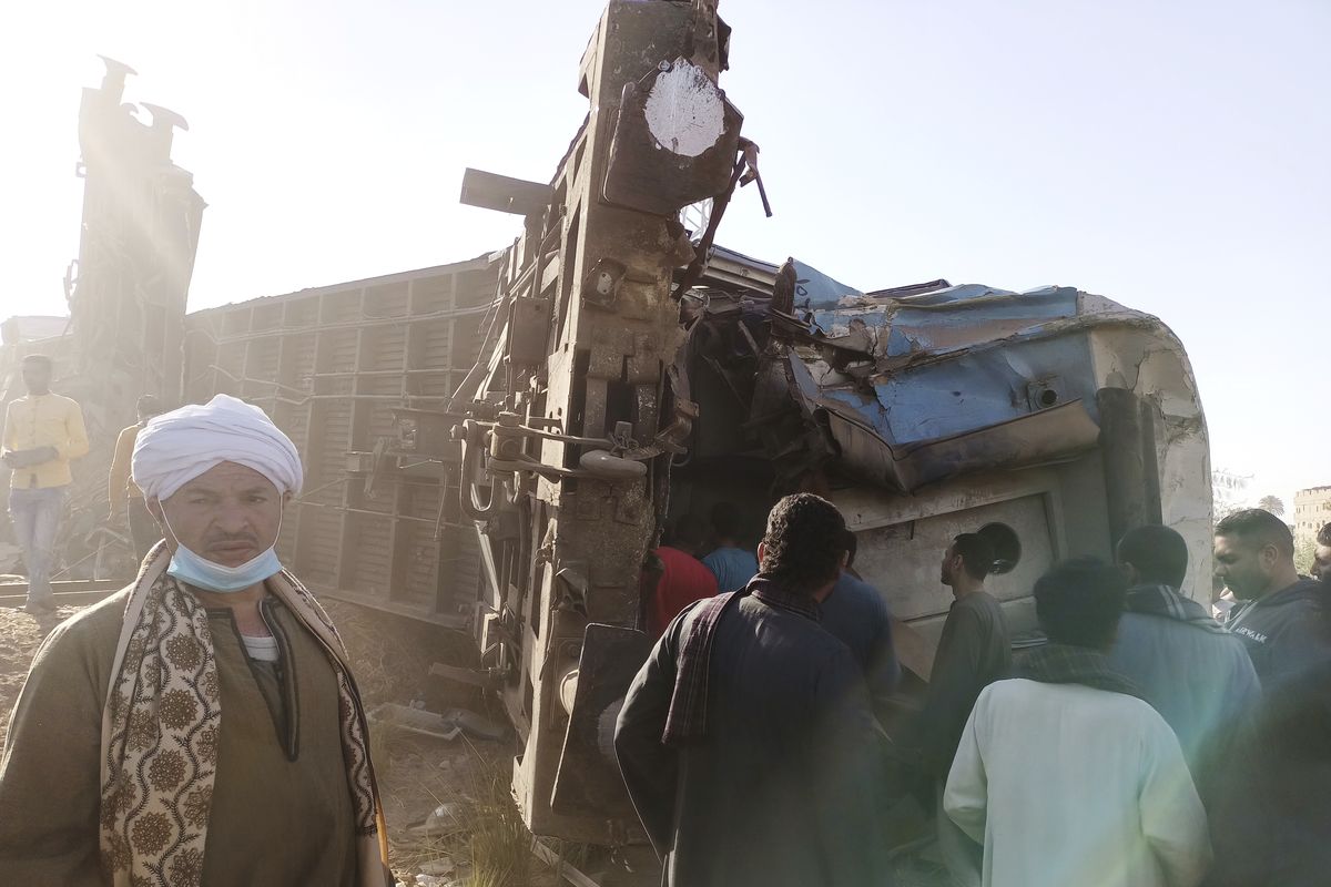Egyptians look for remains of victims around mangled train carriages at the scene of a train accident in Sohag, Egypt, Friday, March 26, 2021. Egyptian officials say two trains collided in southern Egypt in the latest in a series of deadly accidents along Egypt