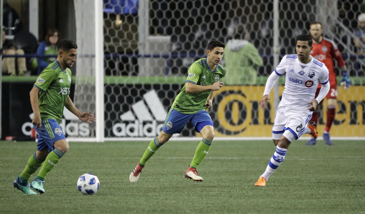 Seattle Sounders midfielder Alex Roldan, center, and his brother, midfielder Cristian Roldan, left, advance the ball during the second half of an MLS soccer match against the Montreal Impact, Saturday, March 31, 2018, in Seattle. The Impact won 1-0. (Ted S. Warren / Associated Press)