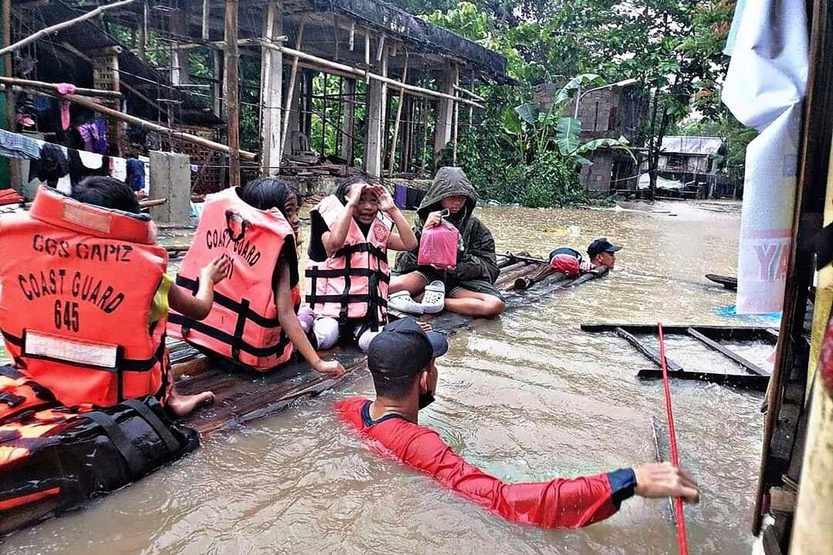 In this handout photo provided by the Philippine Coast Guard, residents are evacuated by rescuers in a flooded village in Panitan, Panay island, Philippines on Tuesday April 12, 2022. Heavy rains caused by a summer tropical depression killed at least several people in the central and southern Philippines, mostly due to landslides, officials said Monday.  (HOGP)