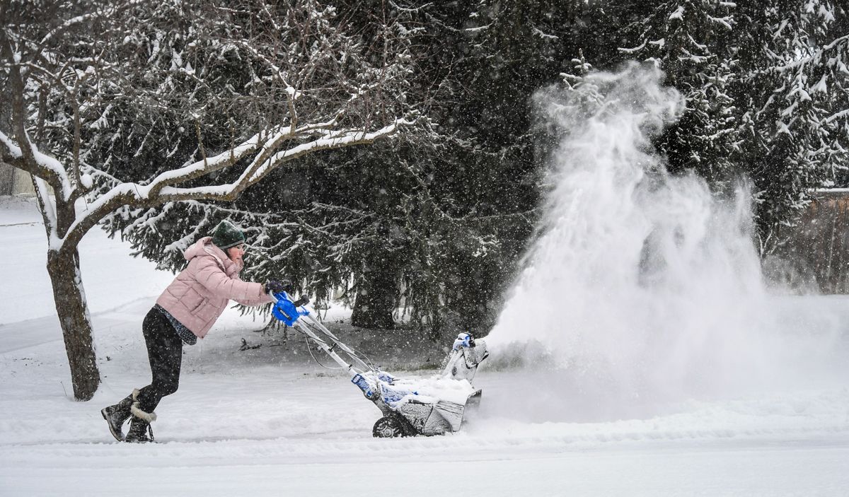 Julie Gehlen battles to push her snow thrower up the incline of her driveway at 37th Avenue and Morrill Drive during Monday morning