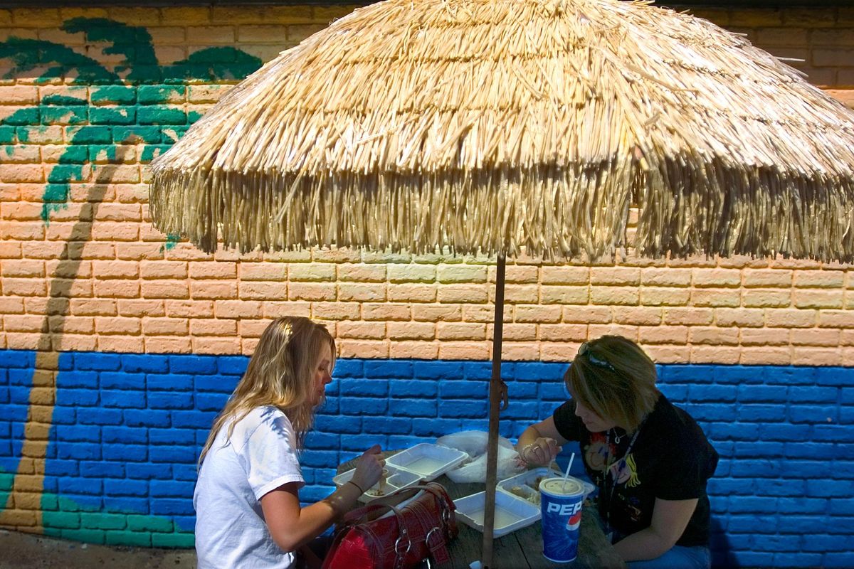 Tiffany Fischer ( left ) and Andrea Smith find some shade under a bamboo umbrella as hot tropical weather smothers Spokane Wednesday May 17. 2006. After more than 60 consecutive days without recorded rainfall, Spokane is on track to crack its second-place record this weekend and first place record next week. (Christopher Anderson / The Spokesman-Review)