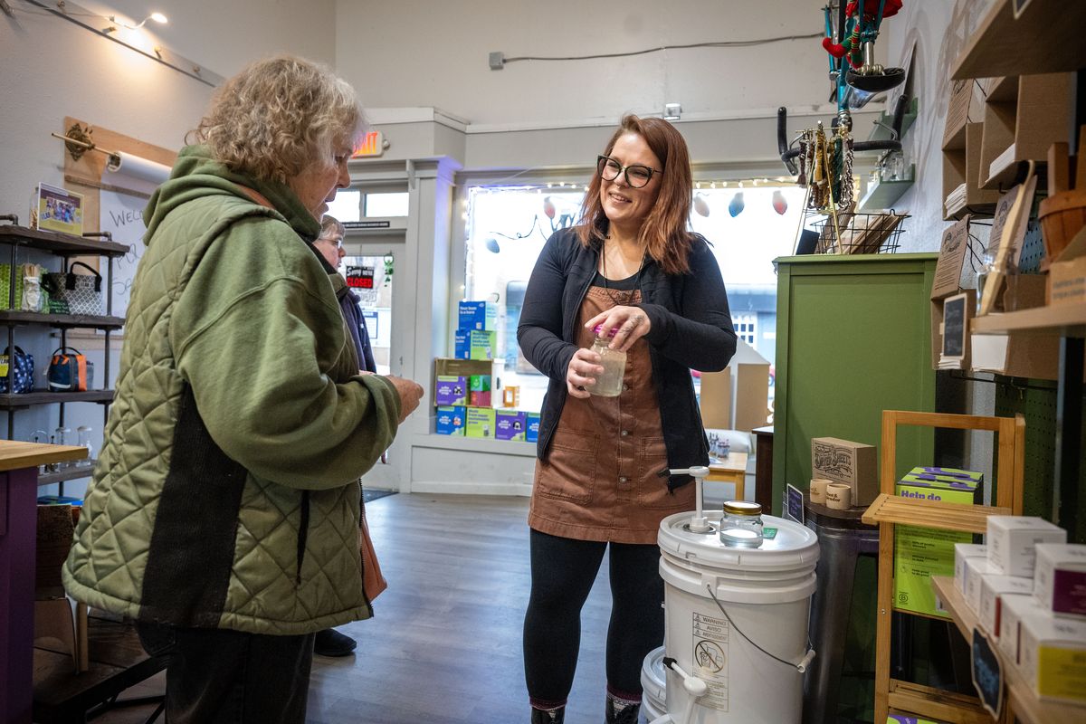 With sustainability in mind, Scarlett Arlt, on right, owner of Evergreen Refillery, helps customer Vickie McMillan fill a repurposed jar with natural dish soap at her shop Dec. 12 in Cheney. (COLIN MULVANY/THE SPOKESMAN-REVIEW)