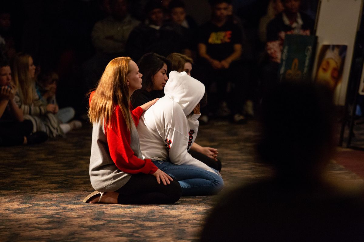 People attending a benefit for Eddie Daniels IIl kneel at the front of the house in memory of Daniels at Healing Hands Ministry on Oct. 21, 2018. Daniels was a 15-year-old student at Lewis and Clark High School and an active member of Youth for Christ. (Libby Kamrowski / The Spokesman-Review)