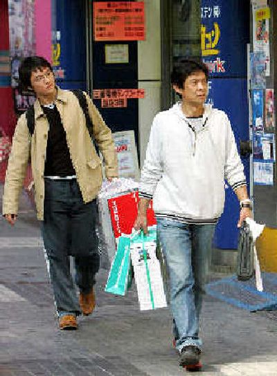 
Shoppers carry packages of their purchase at famed Akihabara electronics and electric shopping district in Tokyo on Thursday. 
 (Associated Press / The Spokesman-Review)
