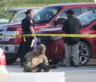 A police officer recovers a rifle while sweeping through the parking lot of a Twin Peaks restaurant Tuesday in Waco, Texas. (Associated Press)