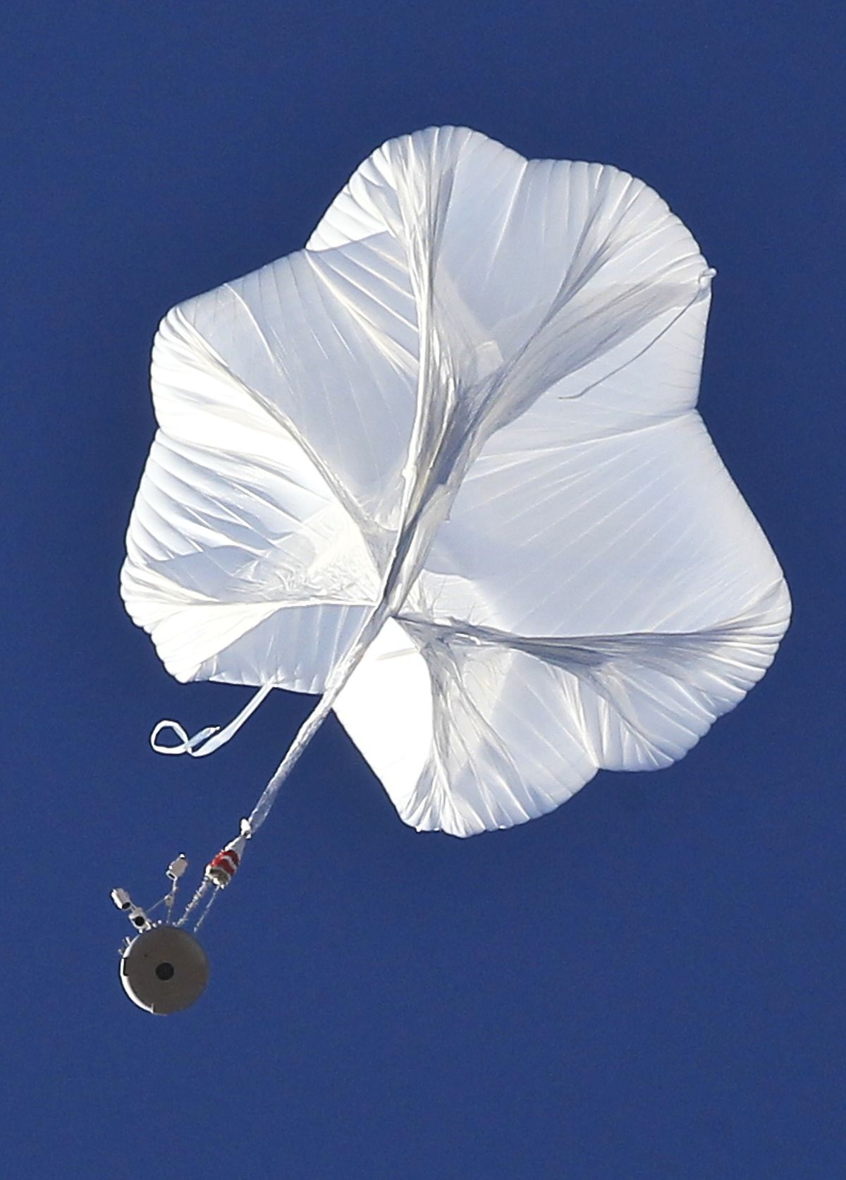 The capsule, bottom left, and attached helium balloon carrying Felix Baumgartner lifts off as he attempts to break the speed of sound with his own body by jumping from a space capsule lifted by a helium balloon, Sunday, Oct. 14, 2012, in Roswell, N.M.  Baumgartner plans to jump from an altitude of 120,000 feet, an altitude chosen to enable him to achieve Mach 1 in free fall, which would deliver scientific data to the aerospace community about human survival from high altitudes. (Ross Franklin / Associated Press)