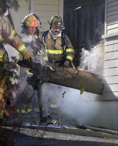 Blaze busters: Spokane Fire Department firefighters pull apart a back deck to put out a fire Tuesday at a home in the 400 block of East 28th Avenue. The fire was confined to the porch, and no one was injured. (CHRISTOPHER ANDERSON / The Spokesman-Review)