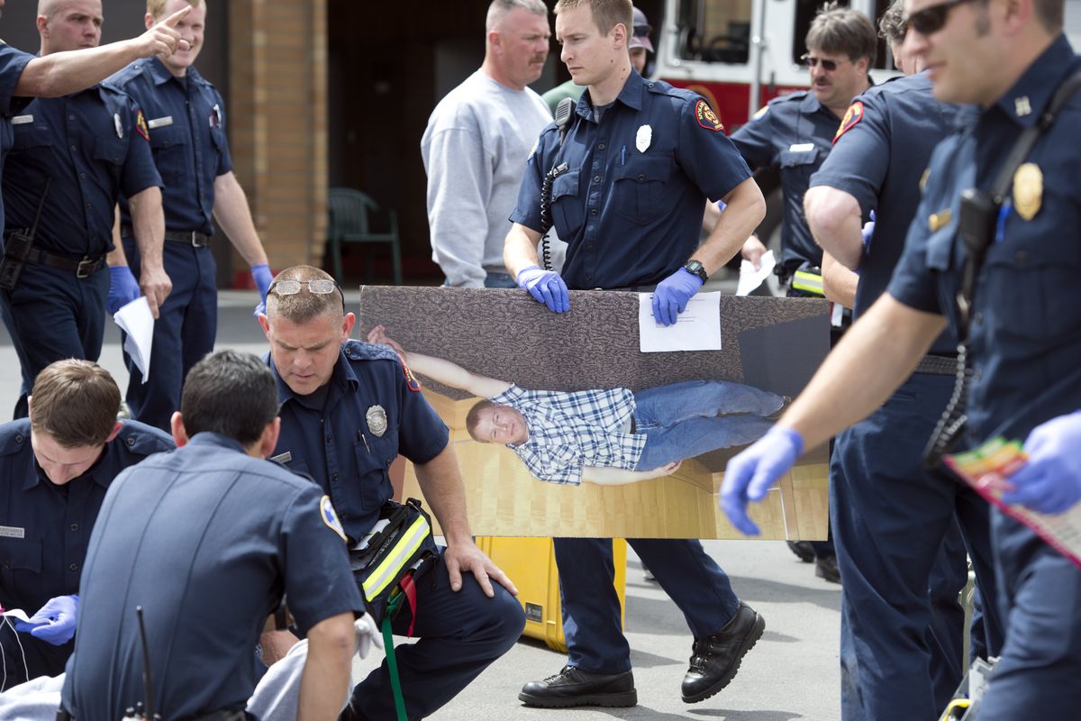 Spokane Valley firefighter Paul Turcotte carries an enlarged photograph that represents a shooting victim as rescue crews participate in a mass casualty training exercise Wednesday at the department’s old administration building. (Dan Pelle)