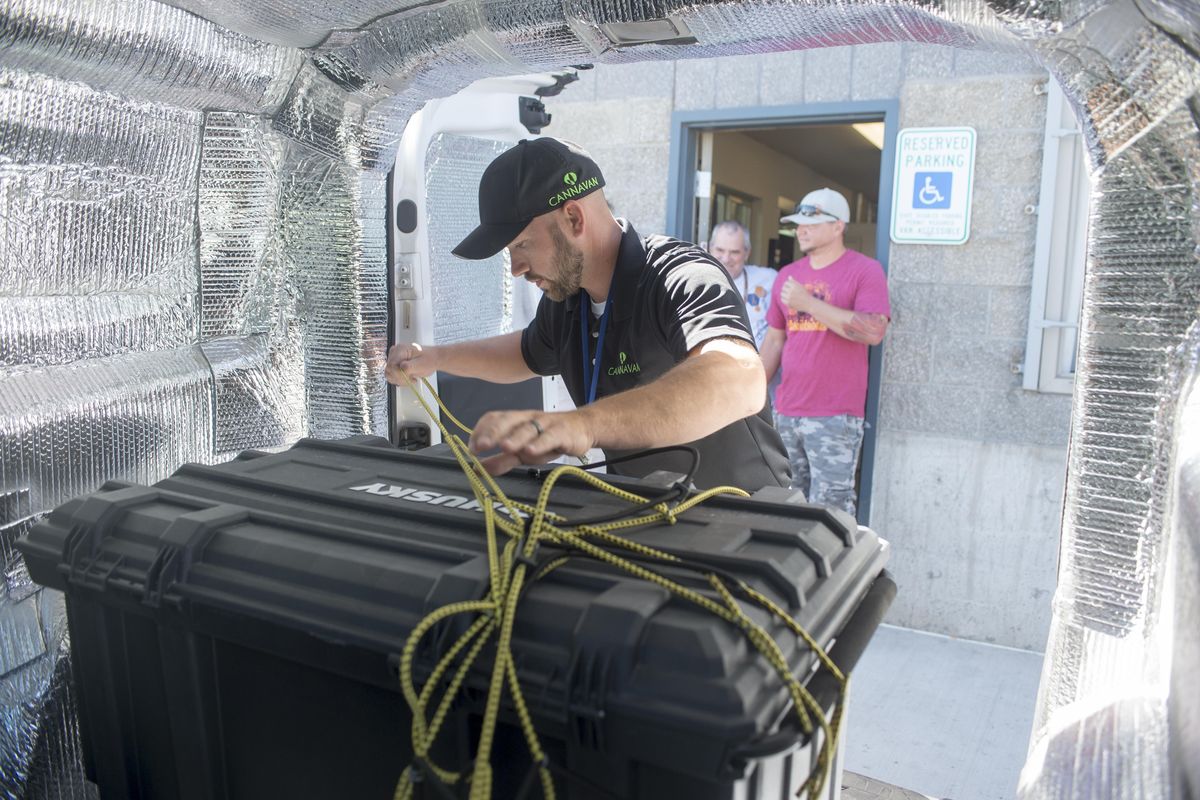 Outside Firehouse Productions, a cannabis producer in Hillyard, transport driver Jon Sahlberg secures a locked plastic tote filled with marijuana products in the back of his van, part of a regular delivery made by his business, Cannavan, Monday, July 31, 2017. This delivery was just across Spokane to a retail store, but he makes about four trips to the Seattle area each week. (Jesse Tinsley / The Spokesman-Review)