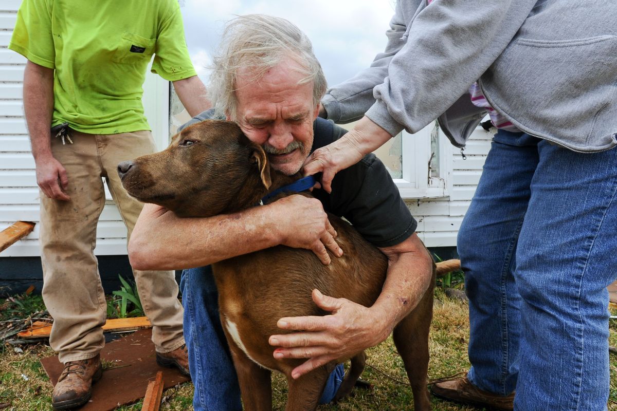 Greg Cook hugs his dog Coco after finding her inside his destroyed home in East Limestone, Ala., on Friday. An outbreak of storms damaged dozens of houses in Alabama and Tennessee. (Associated Press)