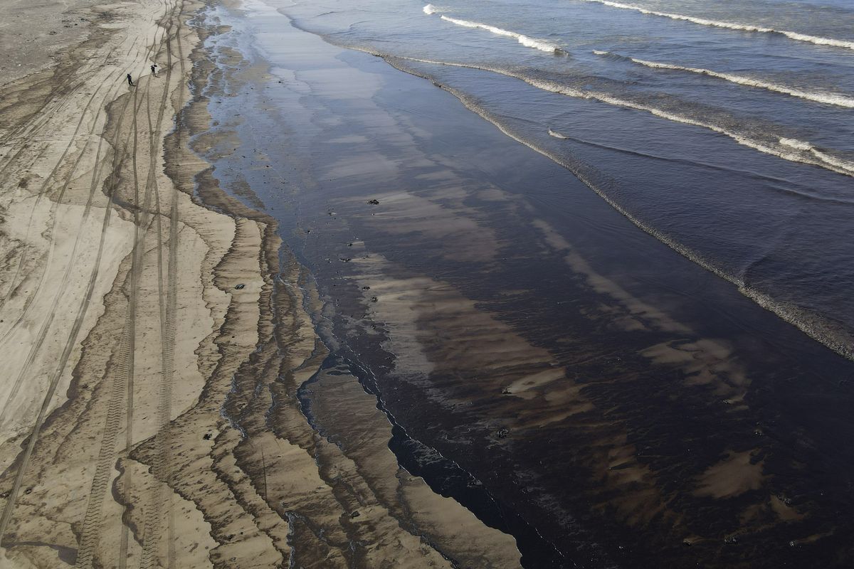 Oil pollutes Cavero beach in Ventanilla, Callao, Peru, Tuesday, Jan. 18, 2022, after high waves attributed to the eruption of an undersea volcano in Tonga caused an oil spill. The Peruvian Civil Defense Institute said in a press release that a ship was loading oil into La Pampilla refinery on the Pacific coast on Sunday when strong waves moved the boat and caused the spill.  (Martin Mejia)