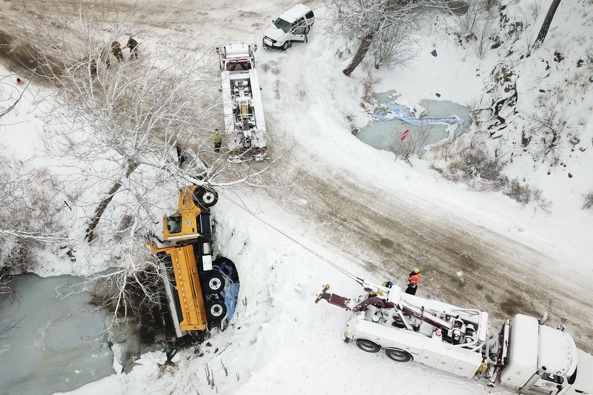 An Okanogan County snowplow slid off an icy road, rolled onto its side and got stuck in a creek about 4 miles west of Omak on Sunday, Jan. 19, 2020. A towing company used two trucks to haul the plow truck out of the water. (Courtesy photo / Okanogan County Emergency Management)