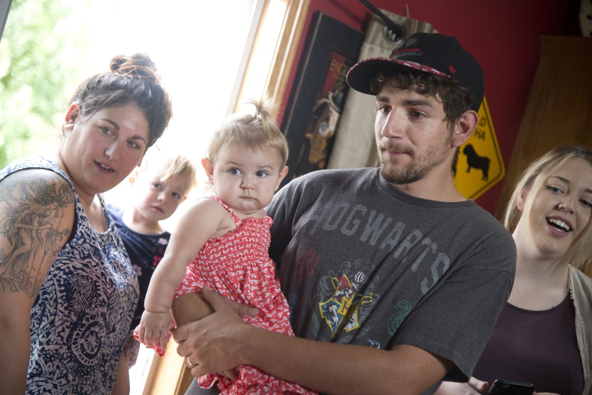 Steve Terrasas, holding his 1-year-old daughter Kylie, stands with friends and family during a birthday party for Kylie and a cousin at his father-in-law’s house in Colbert on Aug. 9.  (Jesse Tinsley)
