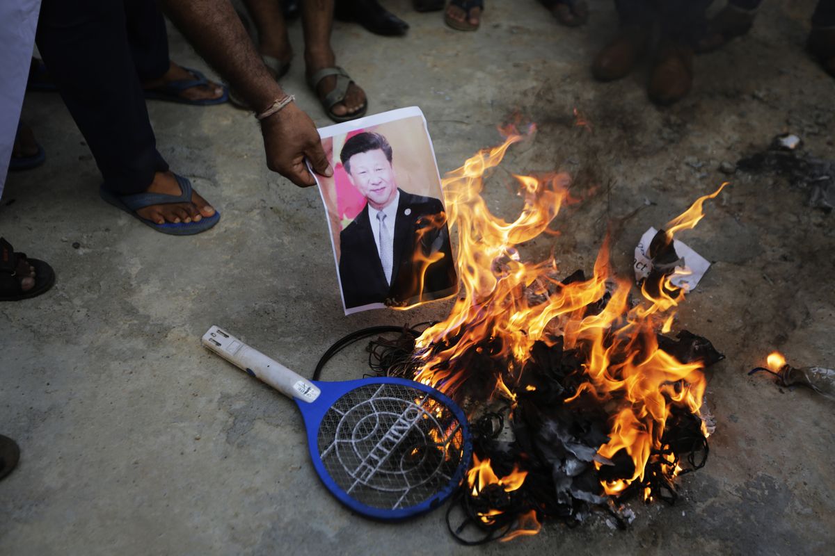 An Indian man burns a photograph of Chinese president Xi Jinping during a protest against China in Ahmedabad, India, Tuesday, June 16, 2020. At least three Indian soldiers, including a senior army officer, were killed in a confrontation with Chinese troops along their disputed border high in the Himalayas where thousands of soldiers on both sides have been facing off for over a month, the Indian army said Tuesday.  (Ajit Solanki)
