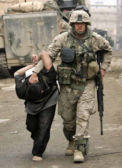 A U.S. Marine leads away a captured Iraqi man in the center of Fallujah, Iraq, on Friday. Many of the city's civilians fled prior to the invasion.
(Associated Press / The Spokesman-Review)