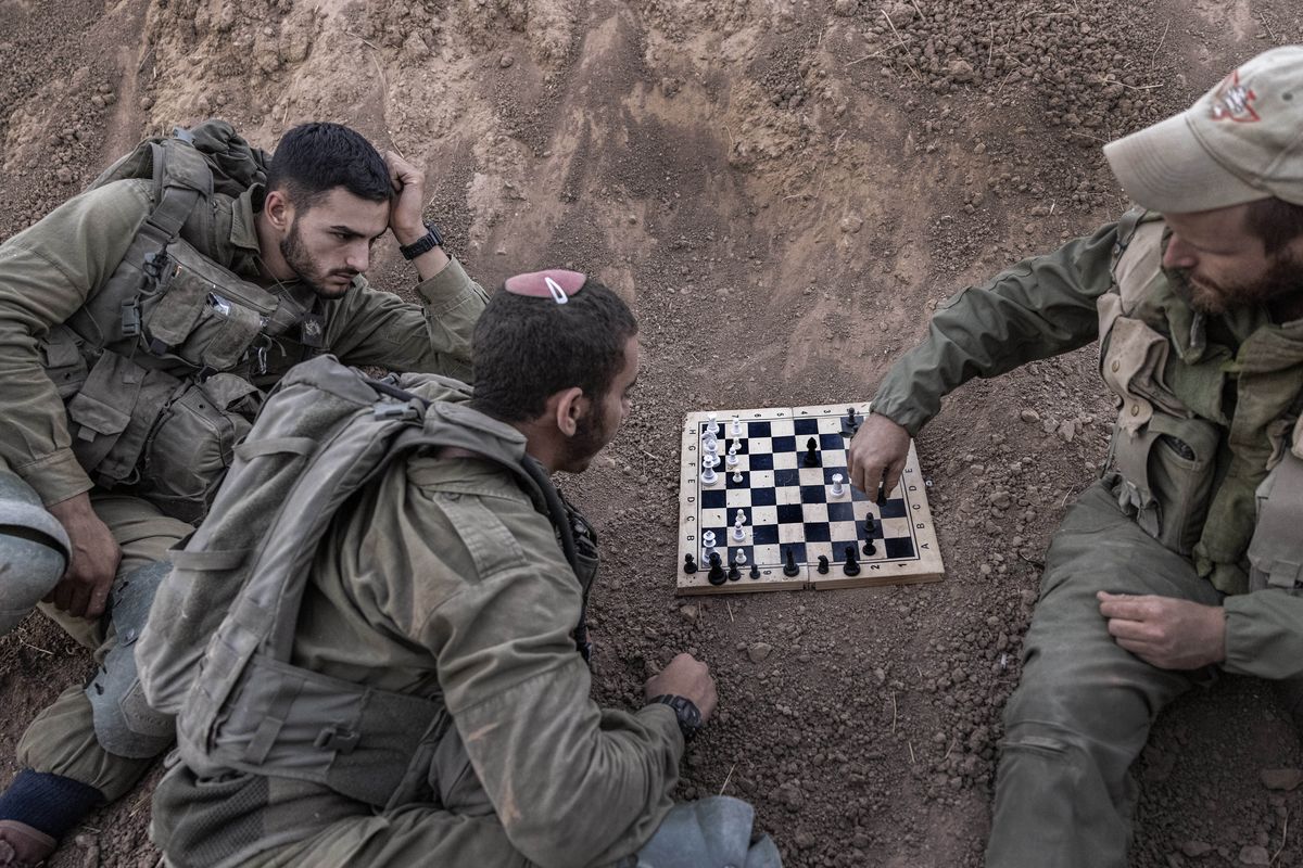 Israeli soldiers play chess at their position near the Israel-Gaza border, Monday, Aug. 16, 2021. Air raid sirens sounded in southern Israel on Monday after a rocket was fired from the Gaza Strip, the first since the 11-day war between Israel and Palestinian militants in May.  (Tsafrir Abayov)