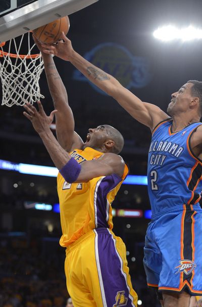 Lakers’ Kobe Bryant, left, puts up a shot as Thunder’s Thabo Sefolosha defends. Bryant scored 36 points in a 99-96 win. (Associated Press)