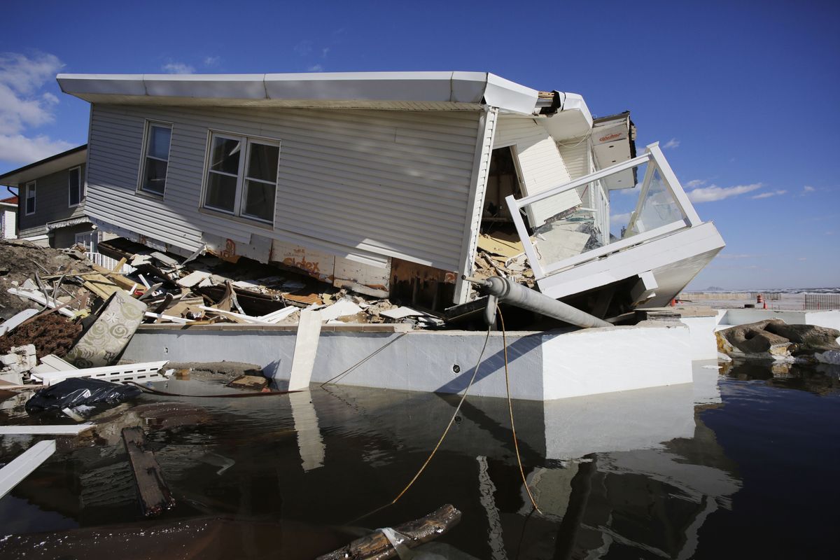 FILE - In this Thursday, Jan. 31, 2013 file photo, a storm-damaged beachfront house is reflected in a pool of water in the Far Rockaways, in the Queens borough of New York. A study released in the journal Nature Communications on Tuesday, May 18, 2021, says climate change added $8 billion to the massive costs of 2012