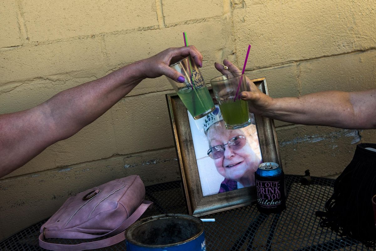 Patrons at Old Mill Bar and Grill raise their drinks in memory of Kathie Bross at the bar in Spokane on Friday, July 14. (Kathy Plonka / The Spokesman-Review)