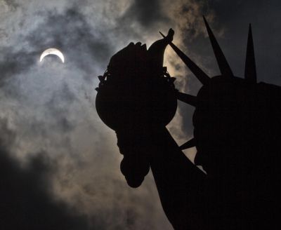 A partial solar eclipse appears over the Statue of Liberty on Liberty Island in New York, on Monday, Aug. 21, 2017. (Associated Press)