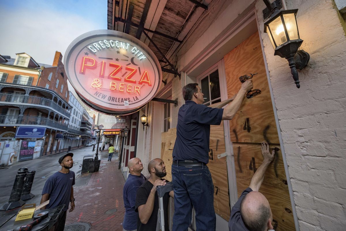 Michael Richard of Creole Cuisine Restaurant Concepts boards up Crescent City Pizza on Bourbon Street in the French Quarter before landfall of Hurricane Ida in New Orleans, Saturday, Aug. 28, 2021. Richard said the group is planning to board up and protect 34 restaurants owned by the company for the storm.  (Matthew Hinton)