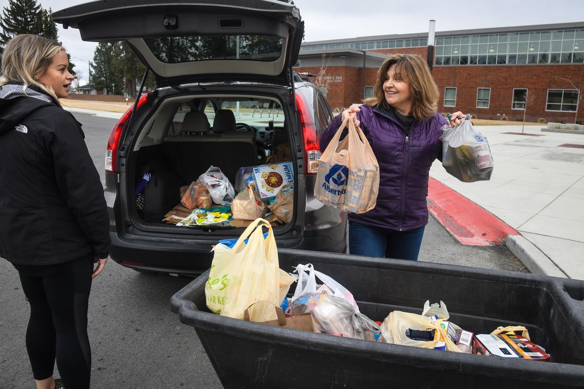 Salk Middle School art teacher Colleen Maciver, right, delivers a load of groceries donated from her Eagle Ridge neighborhood community to the Bite2Go program, at Salk Middle School, Wednesday, April 1, 2020. Salk math teacher and Bite2Go organizer Kendall Erickson is at left. (Dan Pelle / The Spokesman-Review)