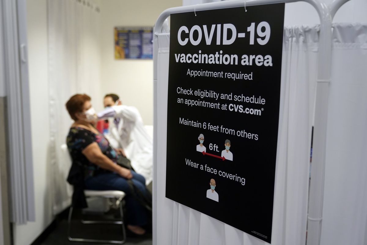 FILE - In this March 1, 2021, file photo, a patient receives a shot of the Moderna COVID-19 vaccine next to a guidelines sign at a CVS Pharmacy branch in Los Angeles. More than 27 million Americans fully vaccinated against the coronavirus will have to keep waiting for guidance from U.S. health officials for what they should and shouldn’t do. The Biden administration said Friday, March 5, it’s focused on getting the guidance right and accommodating emerging science. (Marcio Jose Sanchez)